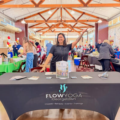 Flow Yoga Georgetown booth at health and lifestyle expo with smiling staff member and promotional materials, Austin Texas