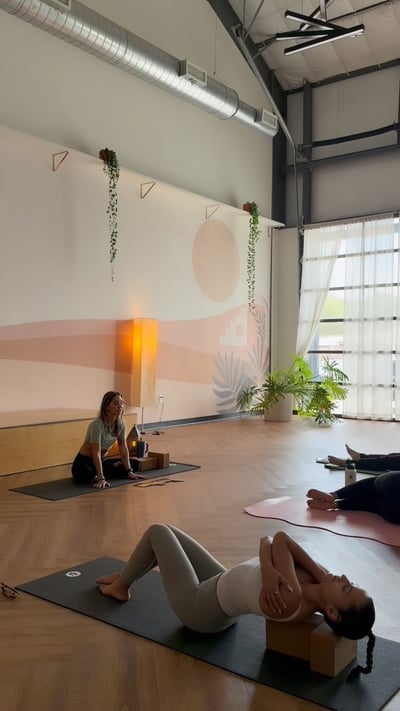 Flow Yoga Cedar Park students practicing restorative yoga with bolsters and blocks in a bright studio, Austin Texas